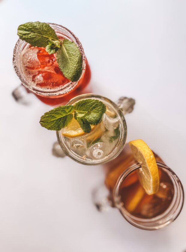 Três copos com drinques com água tônica e diferentes guarnições
