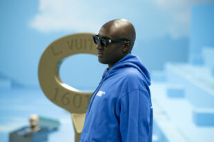 Virgil abloh de moletom com capuz azul em um cenário com paredes pintadas como um céu com nuvens