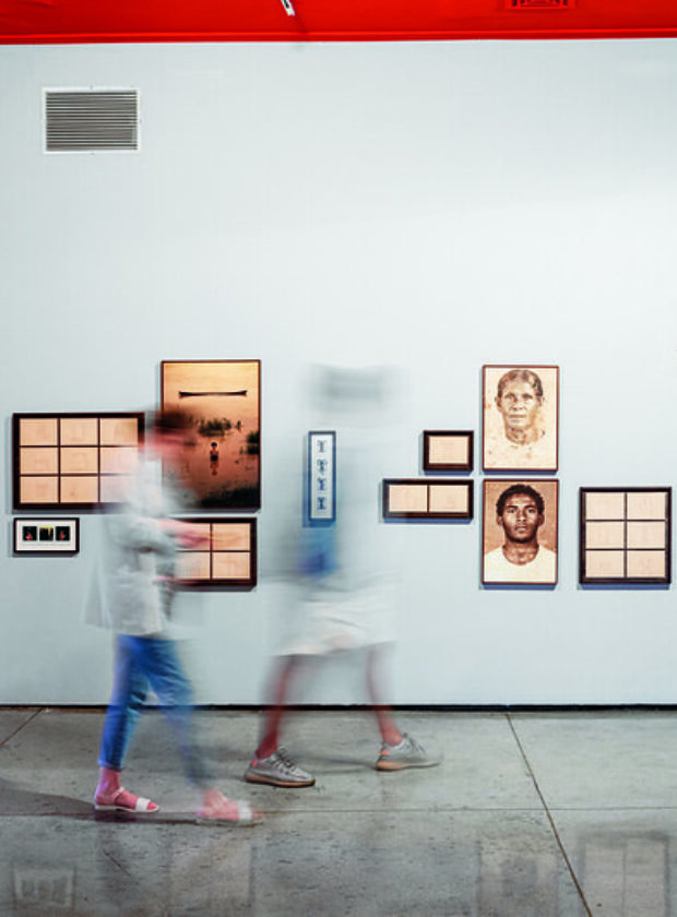 pessoas com imagem borrada passam em frente a obras da Exposição 37 Panorama MAM SP 2022