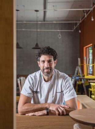 chef rodrigo oliveira sentado na mesa do restaurante mocotó na vila leopoldina