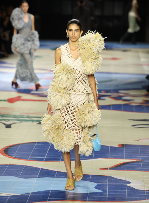 Modelo usa vestido com pompom de ráfia no desfile de verão 2024 da Bottega Veneta durante a semana de moda de Milão.