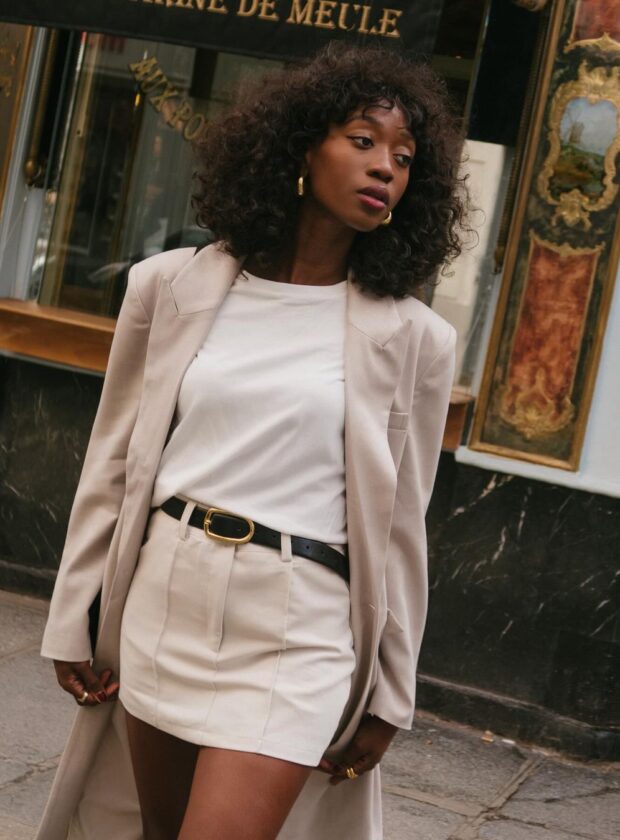 saia de alfaiataria branca curta com camiseta branca básica e casaco longo